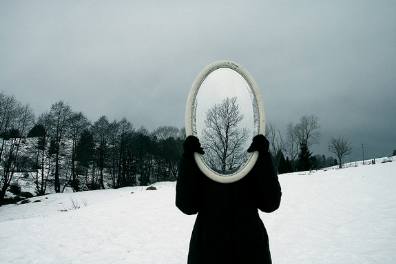 mirror image of head as gray skies and snowy trees
