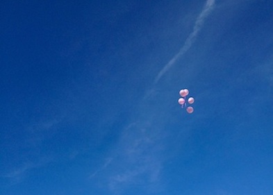 five pink balloons being let go