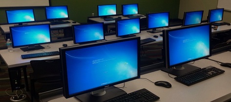 PC computer lab with blue Microsoft office screens seen from standing perspective at an angle