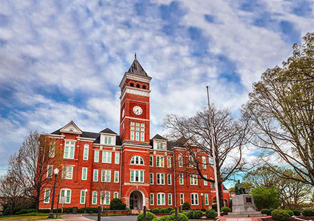 red campus building with a large central clocktower in the middle and two wings