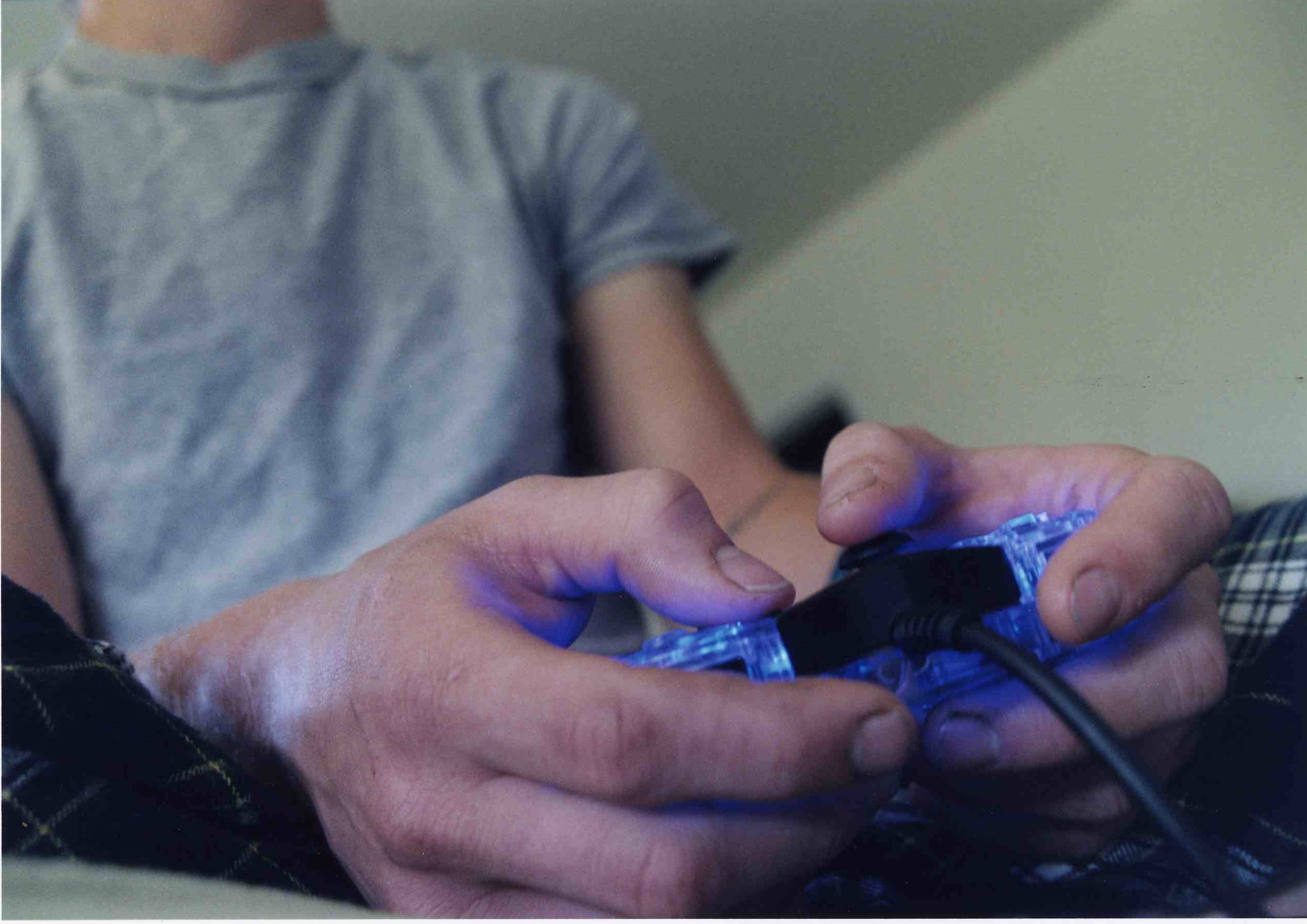 A white male holds a video game controller in his hands