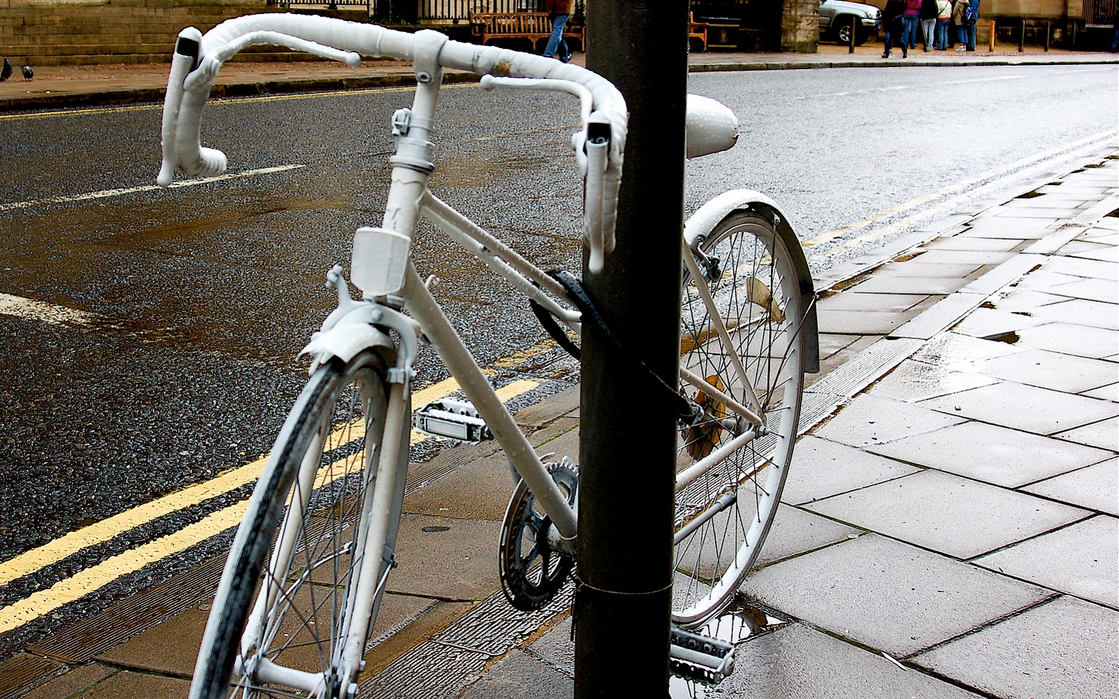 white-painted ghost bike chained to a lamp pole