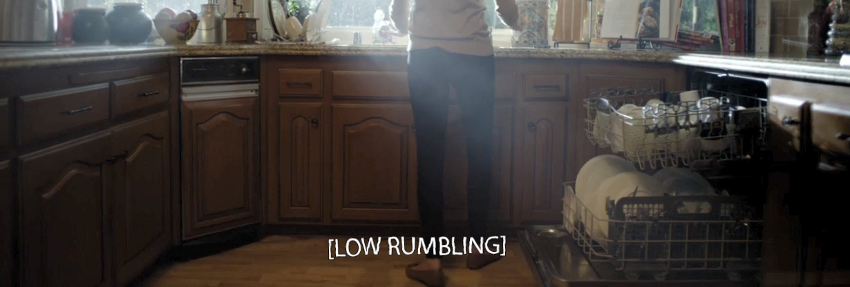 A frame from 10.0 Earthquake featuring a kitchen scene and the caption: [LOW RUMBLING]. The caption has been treated with fractal noise and a shake effect to give it meaning through its rumbling form.