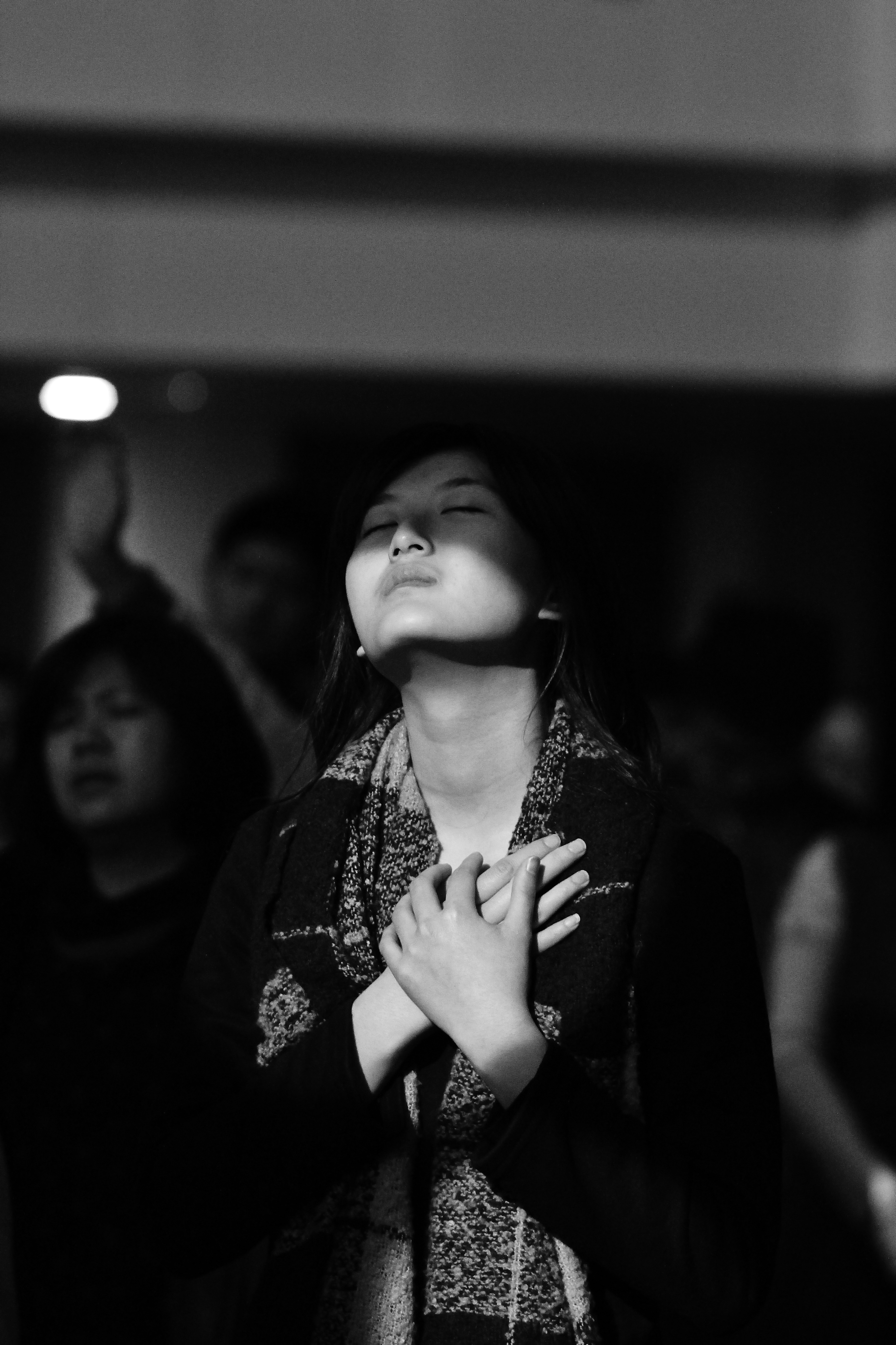 A woman in worship with closed eyes and hands over her heart