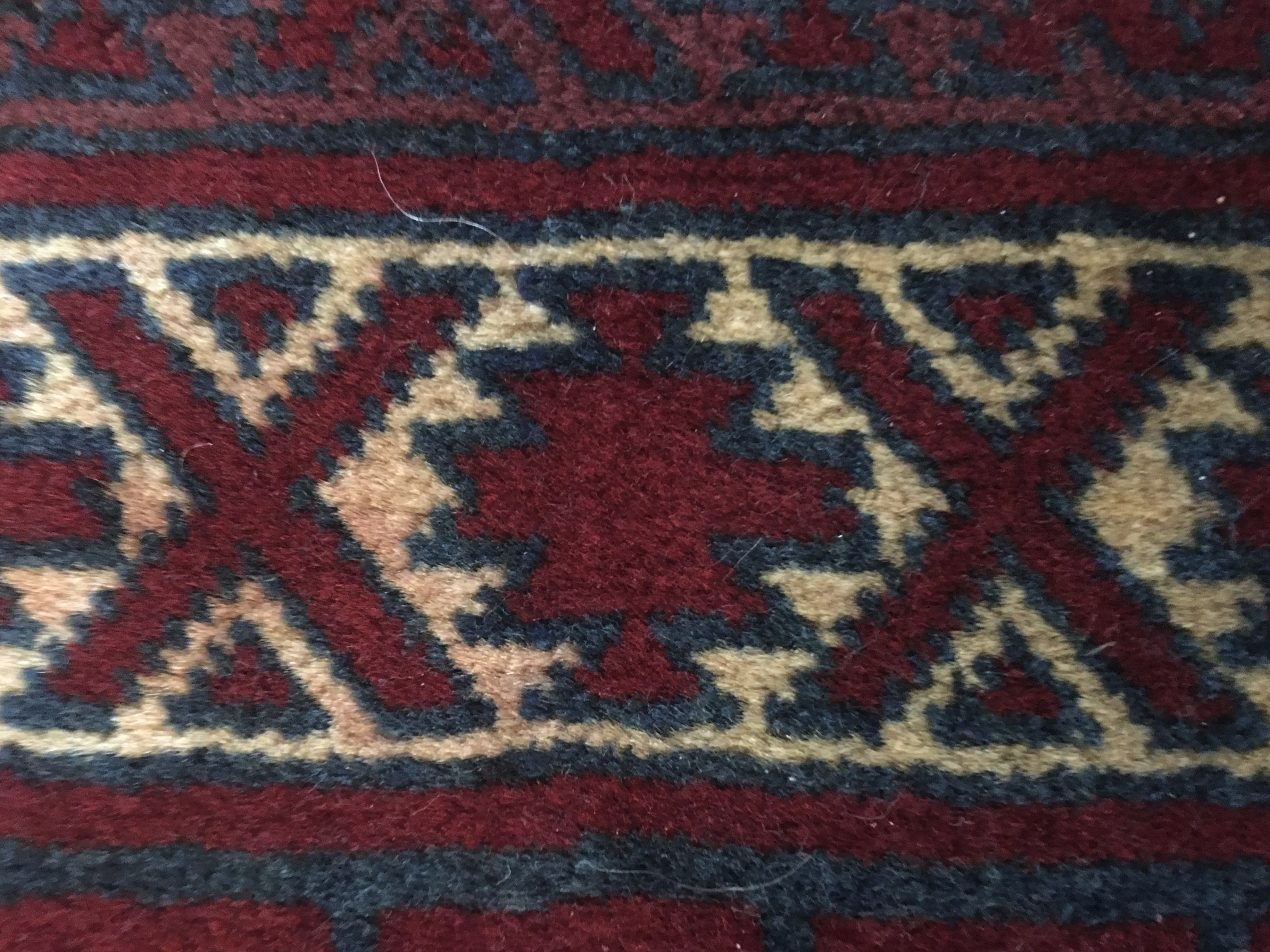 Detail of rug's border with some red dye bleeding into the white background
