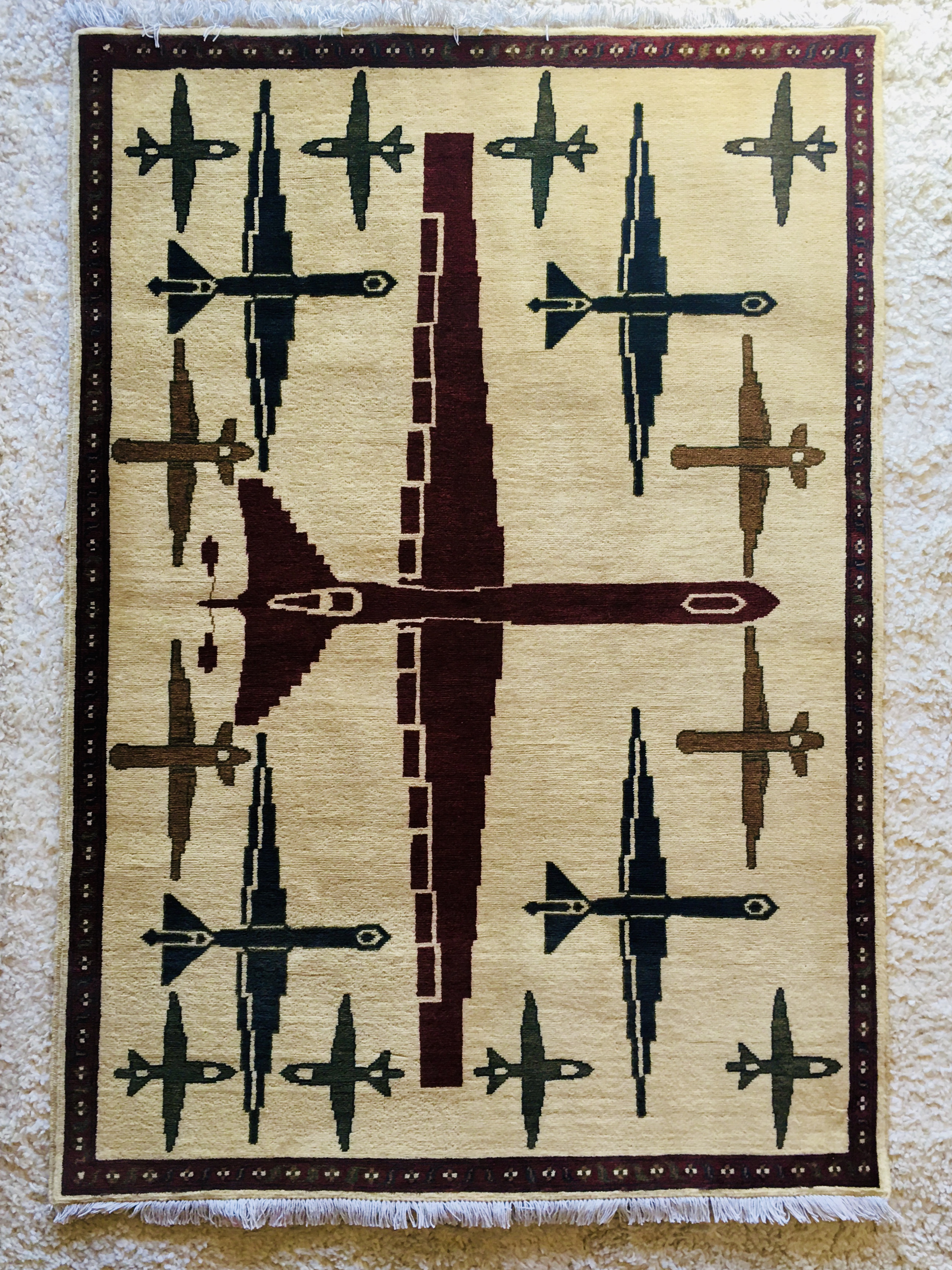 A rug with a soft white background displaying a geometric pattern of war planes in different dark colors