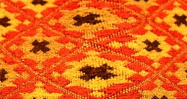 A center section a rug woven by two weavers, one on the left and one on the right, and where their work meets in the middle, the design is distorted.