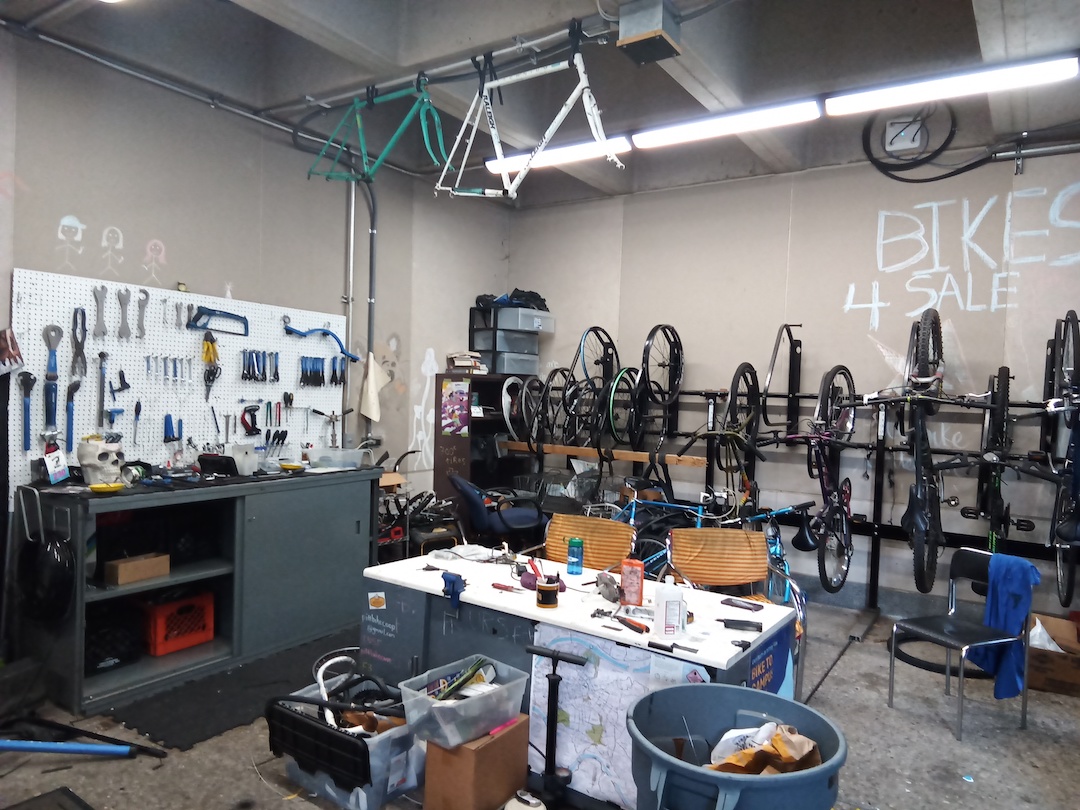 Bike reuse center with refurbished bikes hanging on one wall and a workbench on the other.