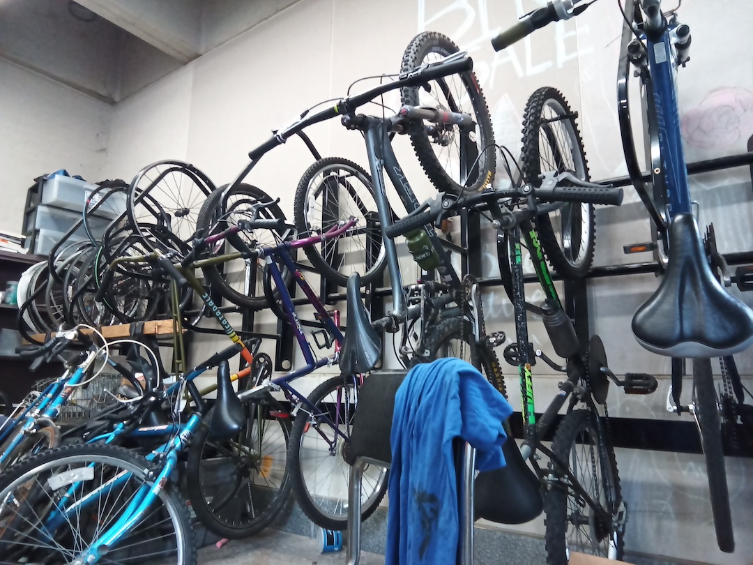 A collection of bikes hanging on a wall in the bike reuse store.