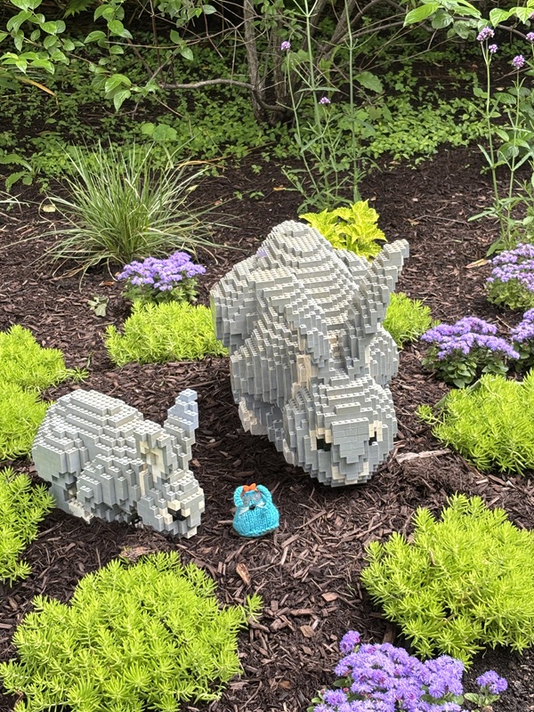 CC standing between two lego rabbits in a garden.