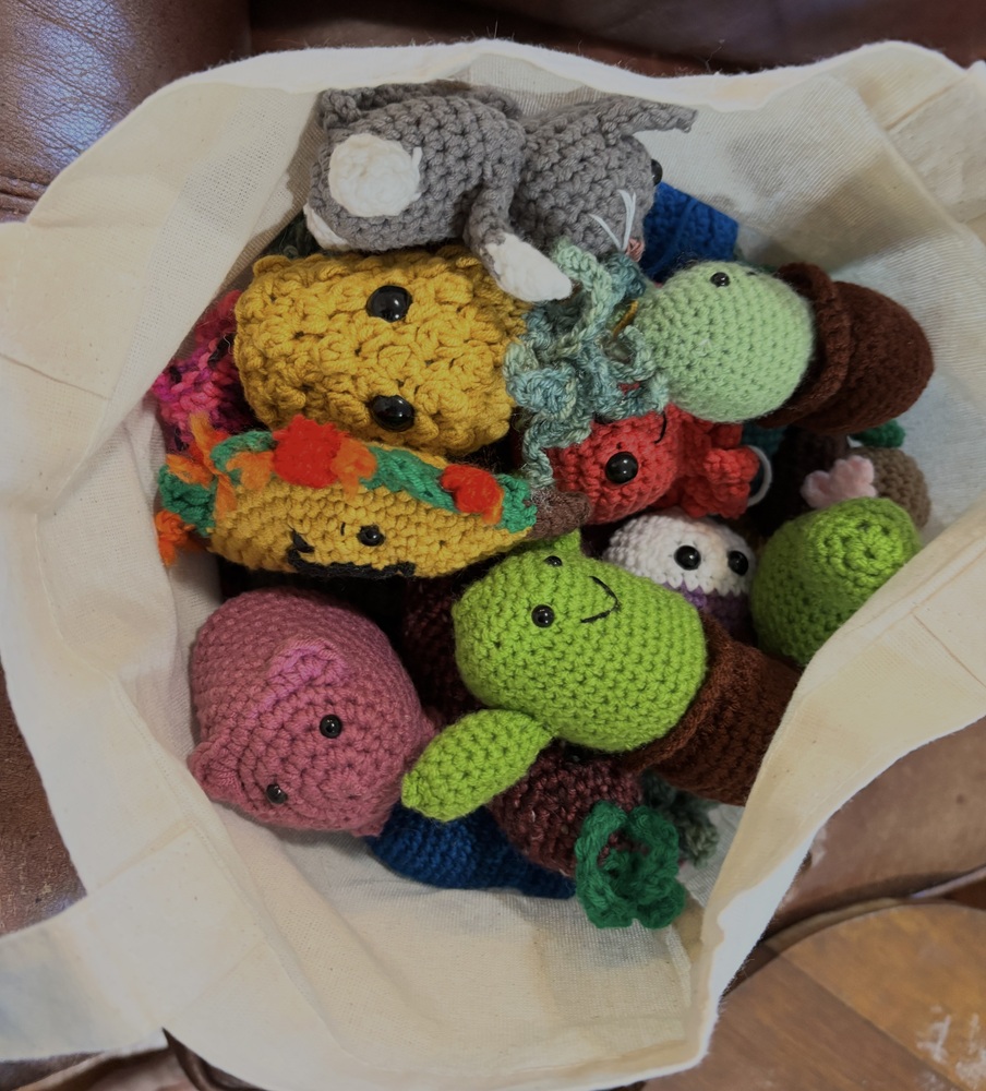 A batch of crochet Conference Creatures in a tote bag.