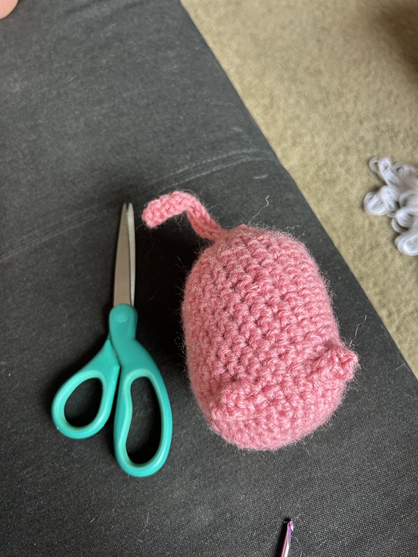 A huge pink creature next to a pair of scissors, that illustrate the creature's size.