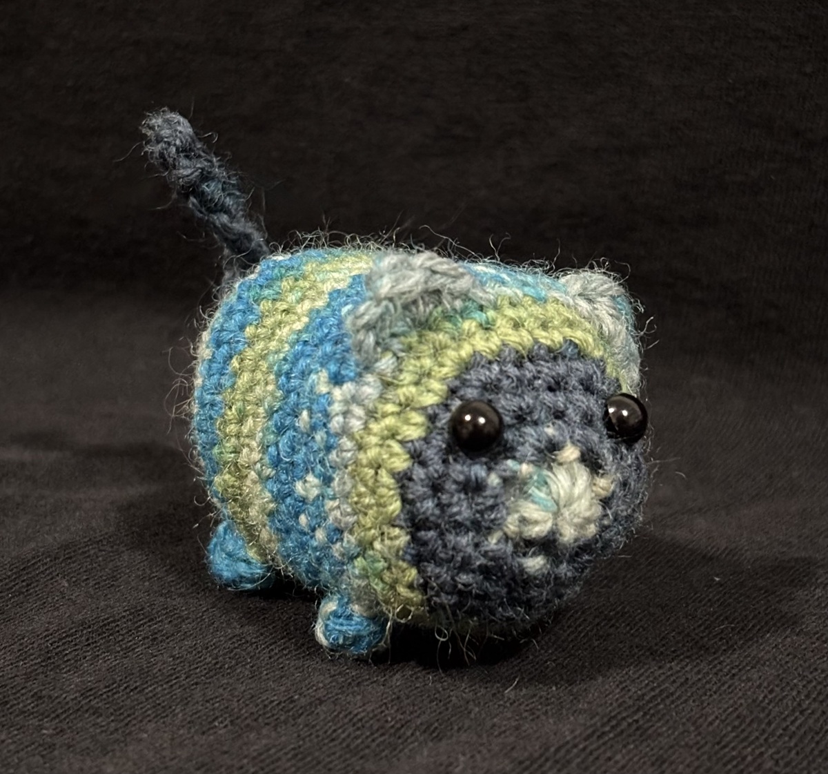 Blue, green, and cream crocheted conference creature.