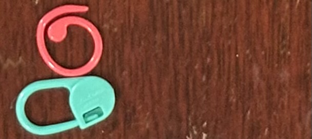 The blue knitted bunny Conference Creatures mascot, CC, standing to the left of a fanned-out pile of CC stickers that say 