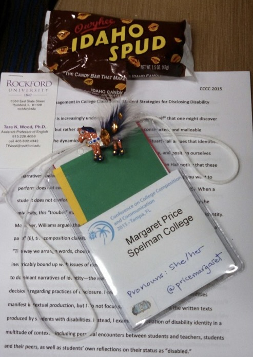 A small, orange and black, sparkly pony with a black furry tail and orange gems lays upon a name badge and conference  presentation script. There is an _Idaho Spud_ candy wrapper above the paper at the top of the frame.