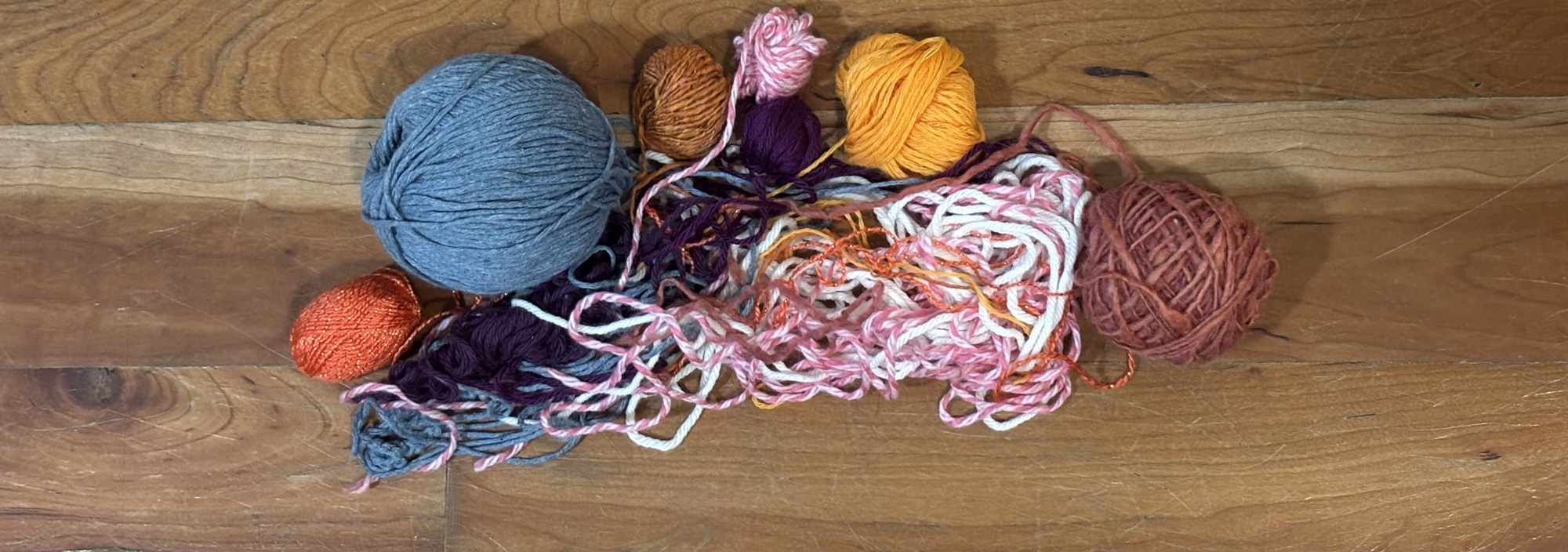 Several partially unraveled skeins yarn that are joined together by their loose ends that have formed a large, multicolored nest.